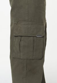 Olivově zelené cargo kalhoty s velkou boční kapsou, vyrobené z odolné tkaniny s hladkou strukturou a s kovovým štítkem s logem.