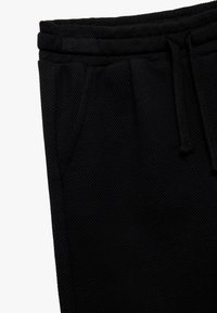Sorte strik joggers med en tekstureret stof, elastisk talje med snor og sidelommer.