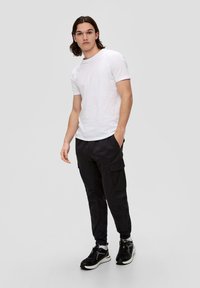 Biała bawełniana koszulka, czarne spodnie cargo z bocznymi kieszeniami oraz czarne trampki z szarymi akcentami. Slim fit i casualowy design.
