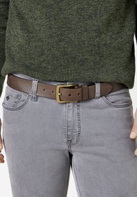 Braun gestreifter Gürtel mit einer Metallschnalle, getragen über grauen Jeans. Der Pullover ist dunkelgrün aus strukturiertem Strickstoff. Fokus auf der Taillenregion.