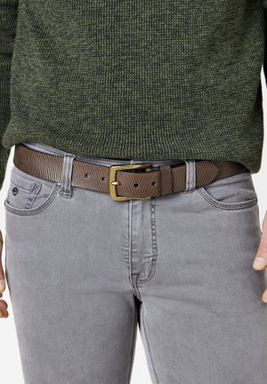 Brown striped belt with a metal buckle, worn over gray jeans. Sweater is dark green, textured knit fabric. Focus on waist region.