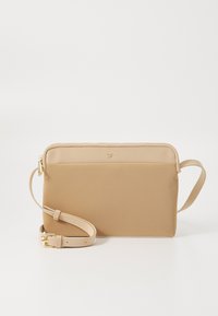Beige Umhängetasche aus glattem Material, mit einem Reißverschluss, einem verstellbaren Tragegurt und einem dezenten Logo an der Vorderseite.