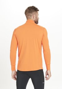 Lang�ærmet atletisk skjorte i klar orange, lavet af letvægtsstof, med flade søm og høj krave for komfort under aktivitet.
