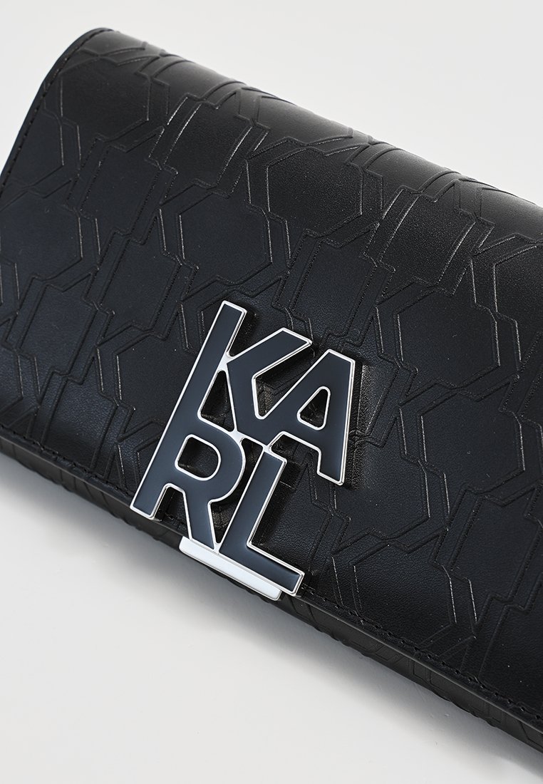 Portefeuille en cuir noir avec un motif géométrique en relief et un logo "KARL" argenté bien en vue à l'avant. Texture lisse, design compact.