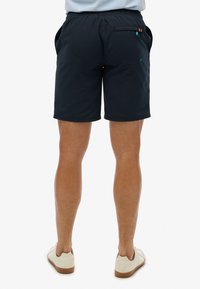 Pantaloni corti blu navy con cintura elastica, tasche laterali e posteriori, e dettagli a contrasto vicino alle tasche. Texture liscia.