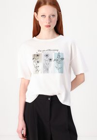 White cotton t-shirt featuring a floral graphic in muted colors with the text "The art of Blooming." Relaxed fit and short sleeves.