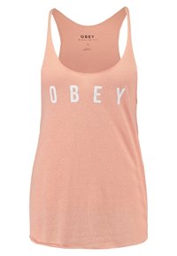 Persikofärgad linne med avslappnad passform, tillverkad av mjukt tyg, med fet vit "OBEY"-text på framsidan i blockstil.