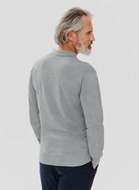 Szary sweter o miękkim materiale, z długimi rękawami, okrągłym dekoltem oraz ściągaczami przy rękawach i dole. Widok z tyłu, o luźnym kroju.