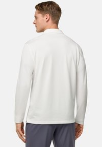 Polo shirt bianco a maniche lunghe con colletto standard, texture liscia, spacchi laterali e branding discreto sull'orlo. Vista posteriore mostrata.