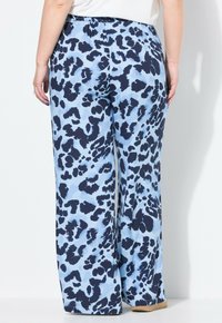 Brettade byxor i ljusblått tyg med ett mörkblått leopardmönster. Har ett elastiskt midjeband och en mjuk textur.