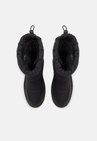 Černé kozačky po kotníky s měkkým, polstrovaným svrškem, elastickým horním okrajem, texturovanou podrážkou a poutkem pro snadné obouvání. Hladký povrch bez ozdob.