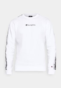 Felpa Champion bianca a maniche lunghe con logo nero sul petto, nastro con marchio lungo le maniche e piccolo logo sul polsino sinistro.