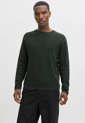 Dunkelgrüner Pullover mit strukturiertem Muster, Rundhalsausschnitt und langen Ärmeln, kombiniert mit schwarzen Hosen. Glattes Material und reguläre Passform.