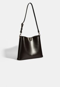 Sac à main en cuir noir avec une texture lisse. Il possède une seule sangle réglable et un fermoir en métal doré en haut.