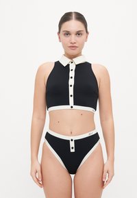 Black two-piece swimwear set featuring a collared crop top with button details and high-waisted bottoms with contrasting cream accents.