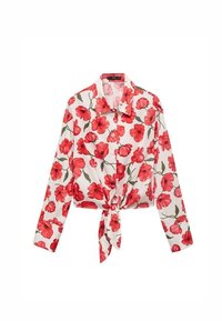Blouse blanche à manches longues avec imprimé floral rouge, nouée en nœud à la taille.