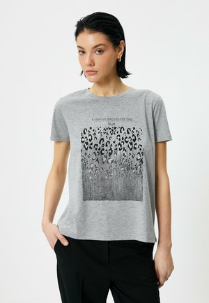 Grå bomulds t-shirt med korte ærmer, der har et sort grafisk print af stiliserede dyremønstre og tekst der læser "Mode begynder på gaden."