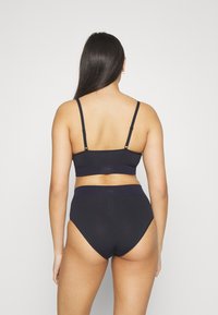 Svart undertøysett med en ryggklips-bralette med justerbare stropper og høytlivs truse. Glatt tekstur med minimal merking.