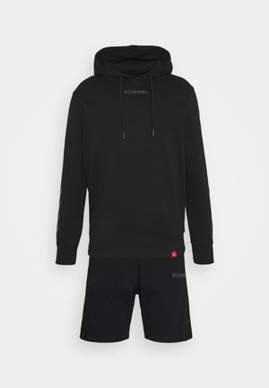 Sweat à capuche noir avec cordons et short noir assorti, tous deux arborant des logos discrets de la marque Hummel.