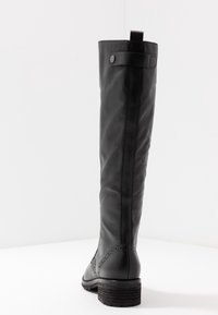 Svart läderknäboot med en texturerad yta, dekorativ sömnadsdetalj nära hälen samt en robust blockklack.