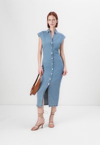 Farmer midi ruha, kapucnival, gallérral, elülső gombos záródással és hasítékkal. Puha kék szín, strukturált fazon. Barna kézitáska és pántos magassarkúk.