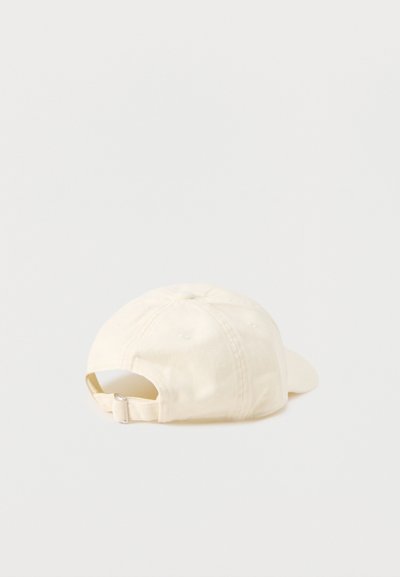 Kremowa bawełniana regulowana czapka z daszkiem, widziana od tyłu, z zapięciem na pasek z metalową klamrą.