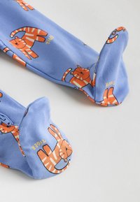 Calzini di cotone blu con motivo di tigri arancioni con volti sorridenti e strisce. La punta è arrotondata e aderente.