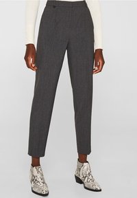Pantalons gris ajustés avec une coupe slim et des plis avant, associés à des bottines blanches à imprimé serpent avec des accents noirs.