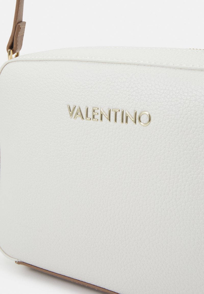 Bolso de hombro de cuero texturizado blanco con logotipo dorado "VALENTINO", con una correa marrón y cierre de cremallera. Forma rectangular compacta.