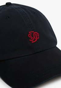 Gorra de algodón negra con visera curva, que presenta un logo bordado en rojo en el frente y orificios de ventilación en la parte superior.