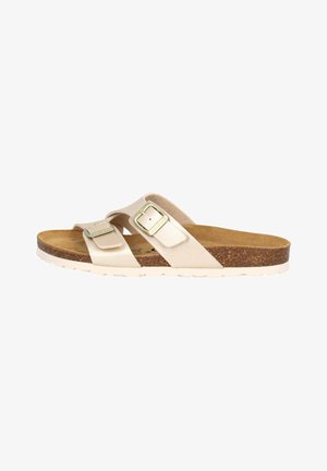 Beige leather slide sandal with two adjustable buckles, cork footbed, textured insole, and white rubber sole. Smooth finish and flat design.