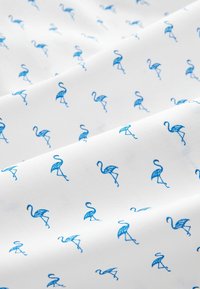 Tejido blanco con un patrón repetido de pequeños flamencos azules con detalles intrincados, dispuestos en una cuadrícula uniforme por toda la superficie.
