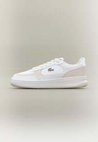 Sapatilhas brancas em pele com um discreto pormenor em camurça bege, apresentando uma sola de borracha texturizada, atacadores brancos e um logótipo dourado da Lacoste de lado.