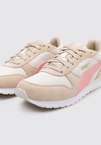 Zapatillas beige y blancas hechas de malla y gamuza, con un logo lateral rosa, punta redondeada y suela texturizada. Los cordones complementan el diseño.