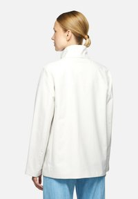 Giacca bianca leggera con colletto alto e maniche lunghe. Il design presenta una texture liscia e una vestibilità comoda.