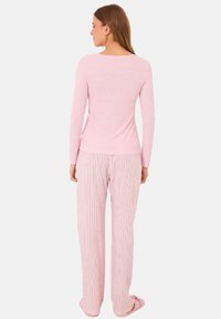 Pink long-sleeve top with a ribbed texture paired with loose, striped pajama pants. Fabric appears soft, lightweight, and comfortable.