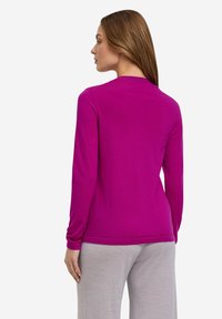 Fitted langetermijn top in levendig fuchsia, gemaakt van een zachte stof met een eenvoudige uitstraling en ronde halslijn, gecombineerd met grijze onderkleding.