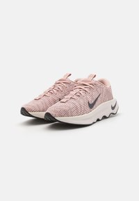Nike løpesko i lys rosa med teksturert stoff, hvit mellomsåle, svart yttersåle og mørkeblå logo. Snøresystem, avrundet form.