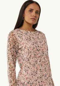 Langärmliges Oberteil mit floralem Muster aus weichem, transparentem Stoff; Pastellnuancen von Rosa, Braun und Creme; runder Ausschnitt und dezente Steppdetails.