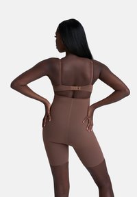 Shapewear marrone con un design aderente, spalline regolabili e chiusura a gancio sulla schiena. Texture liscia e taglio fino al ginocchio.