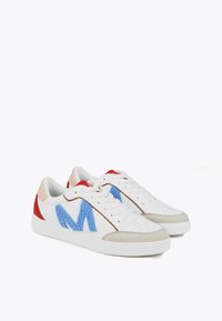 White sneakers with blue and red accents. Features a fluffy blue logo, leather upper, textured beige toe cap, and rubber sole.