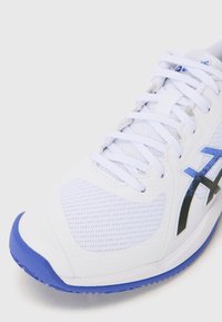 White athletic shoe with a mesh upper, blue rubber sole, and black accents on the side. Features traditional lacing and textured surface.