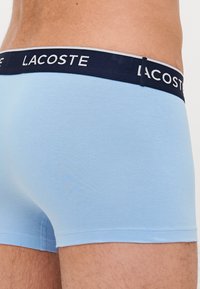 Boxers de color azul claro con una cinturilla elástica en navy que presenta el logo de "Lacoste" en blanco. Tejido suave con un ajuste ceñido y costuras planas.