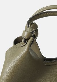 Geantă de mână din piele de culoare verde olive, cu o suprafață texturată, având o formă rotunjită și două mânere scurte cu un detaliu de nod din piele.
