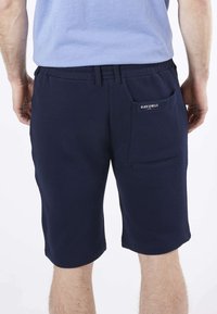 Shorts bleu marine en matériau doux, dotés d'une poche arrière et d'une taille élastique pour le confort. Design simple sans motifs.