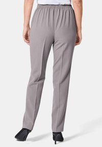 Graue Hose mit elastischem Bund und geradem Schnitt, glatte Textur und minimalistischer Gestaltung. Getragen mit schwarzen High Heels.