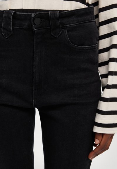 Visoko pasovi črni jeans iz denima z gladko teksturo, zasnova s petimi žepi in gumbasto zapiranje. V paru s črtasto srajco z dolgimi rokavi.