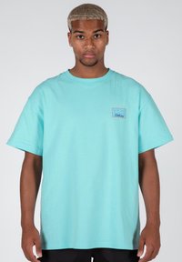 Camiseta de algodón de manga corta en azul claro, con un pequeño detalle en forma de rectángulo que incluye el texto "WRONG WORDS Clothing."