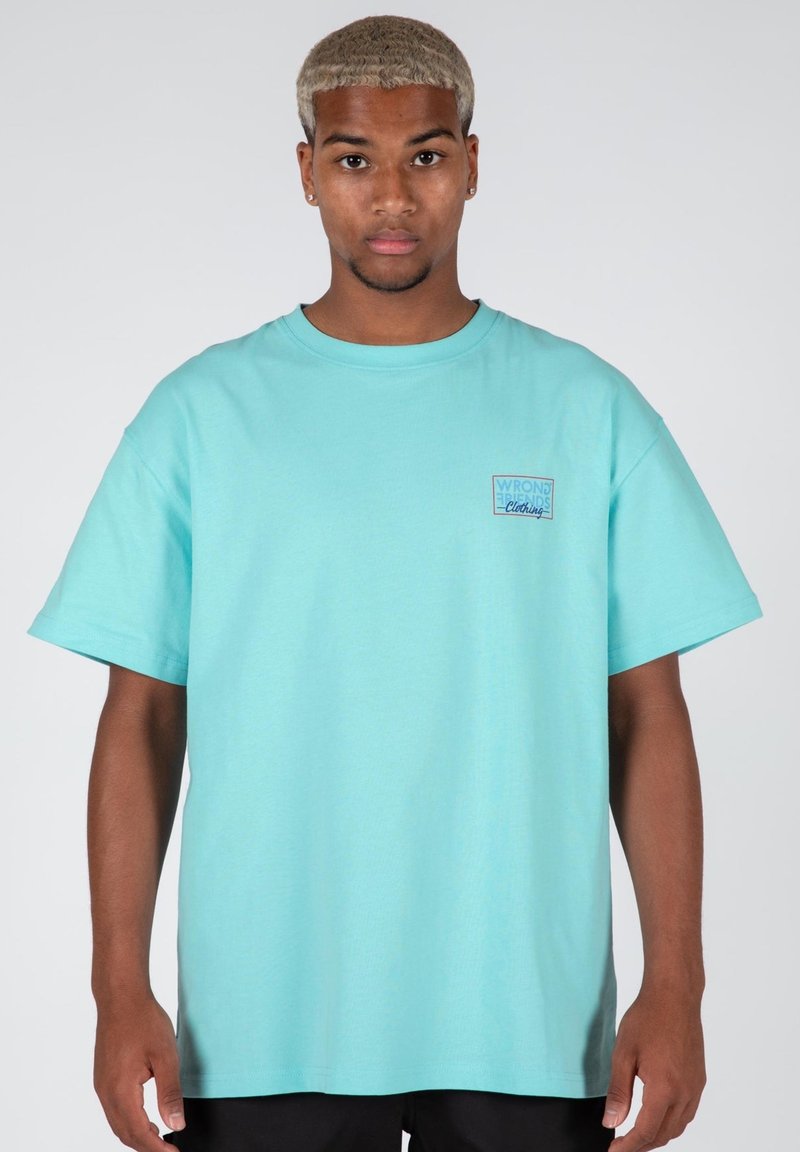 Camiseta de algodón de manga corta en azul claro, con un pequeño detalle en forma de rectángulo que incluye el texto "WRONG WORDS Clothing."