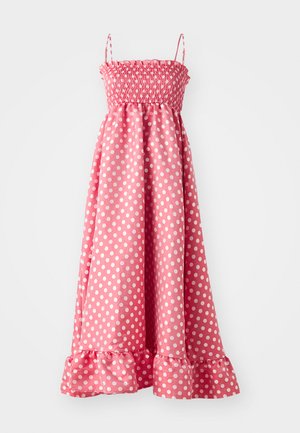 Pink polka dot dress with smocked bodice, thin straps, and a ruffled hem. Made of lightweight fabric, features white polka dots throughout.